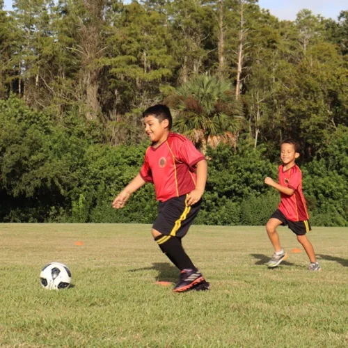 hero mobile Kid with the uniform of grit soccer academy, kicking the ball