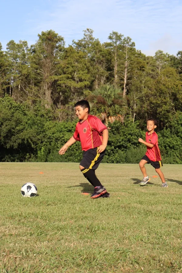 Kid with the uniform of grit soccer academy, kicking the ball